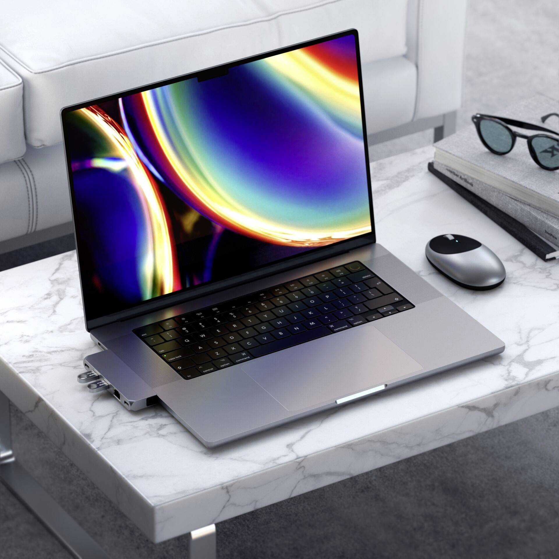 Een laptop staat aangezet op een witte tafel naast een draadloze muis. Het scherm toont een kleurrijk patroon.