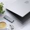 Laptop opengevouwen, ernaast een USB-C-hub, sleutels, koffiekopje en plant op een tafel. Focus op werkplek-setup.
