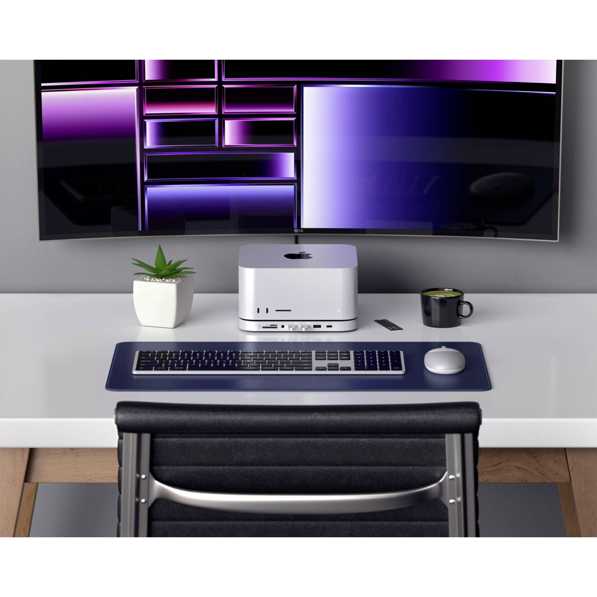 Een moderne bureau met computer, toetsenbord, muis en beeldscherm. Links op de tafel staan een plant en een koffie.