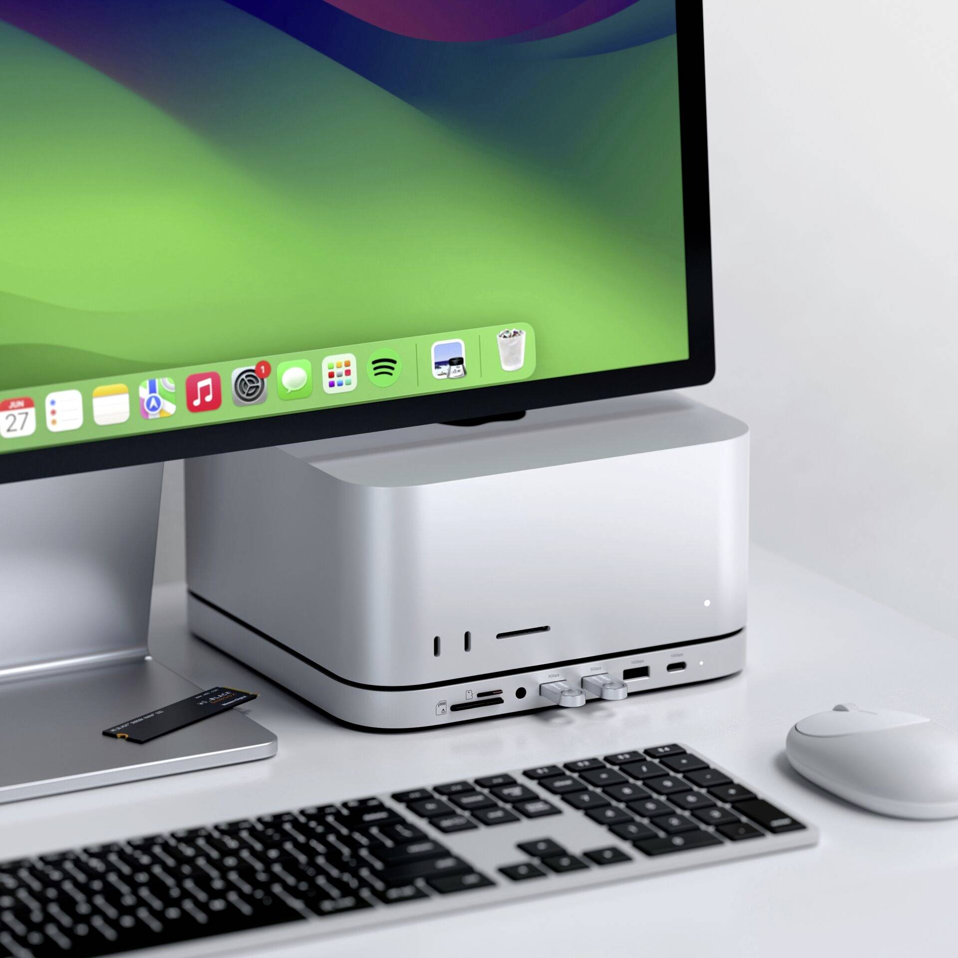 Een moderne computerworkspace met toetsenbord, muis en een groot beeldscherm dat kleurrijke bureaubladpictogrammen toont, op een elegante tafel.