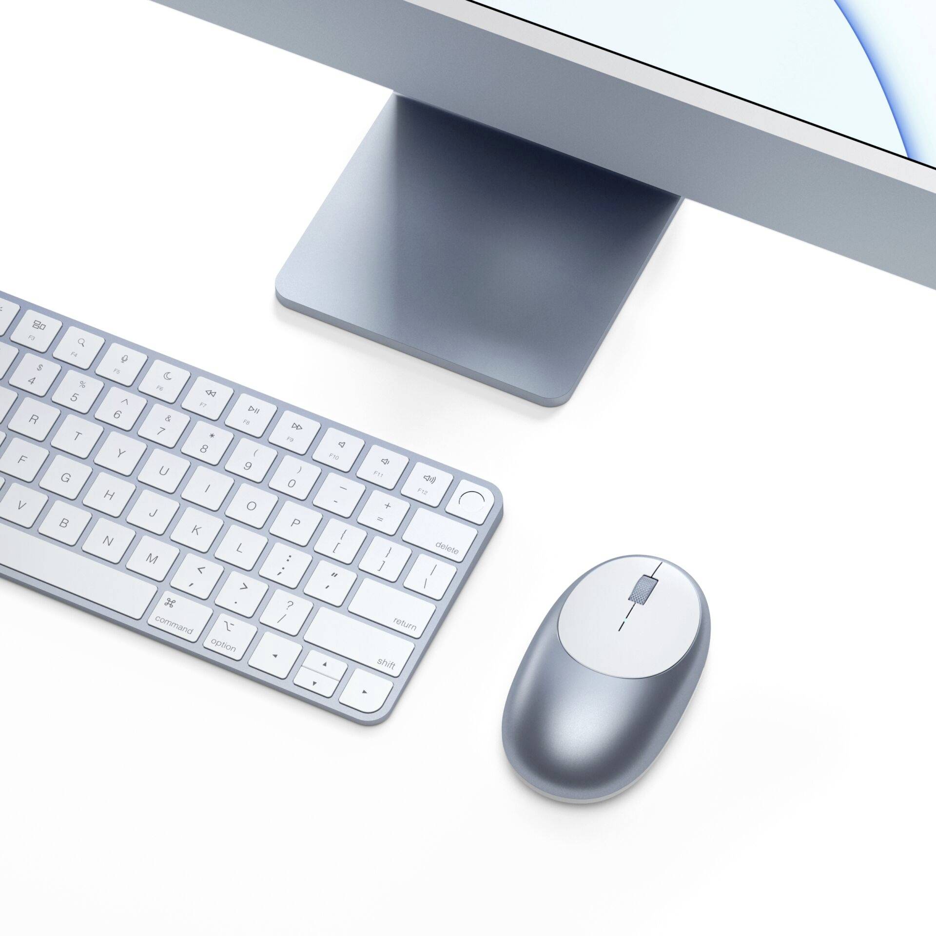 Computertoetsenbord en muis op een witte tafel, naast een moderne monitor. Ideaal voor een minimalistisch werkplekontwerp.