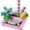 Speelgoed-typemachine van LEGO in roze met witte toetsen, kleurrijke bloemen en een vel papier met 'Er was eens...' op de achtergrond.