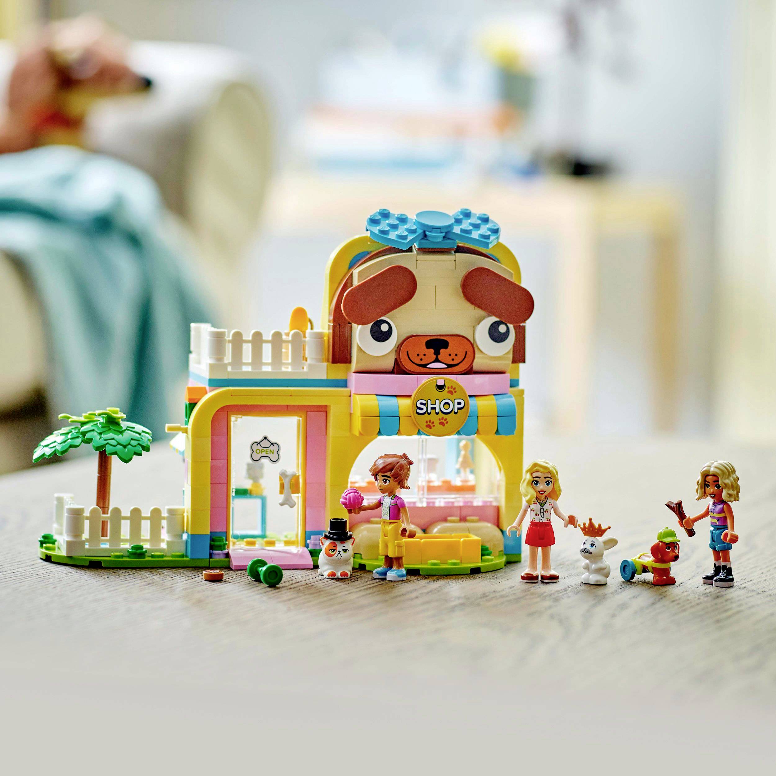 Een kleurrijke speelgoedset toont een winkel in de vorm van een hondenkop met figuren. Kinderen spelen met dieren en miniatuuraccessoires.