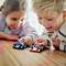 Twee kinderen spelen met speelgoedauto's op een houten tafel, glimlachen en zijn enthousiast. De auto's hebben gekleurde stickers.