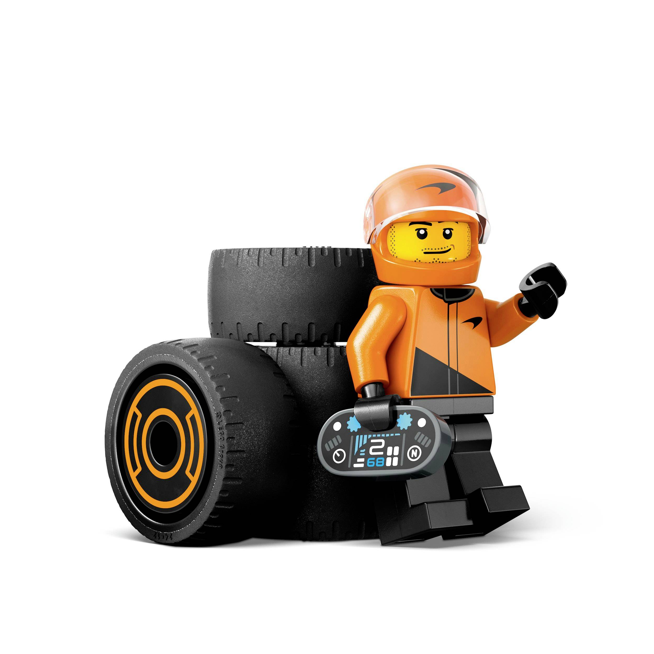 Een Lego-poppetje in een oranje racepak leunt tegen een band en houdt een afstandsbediening vast.