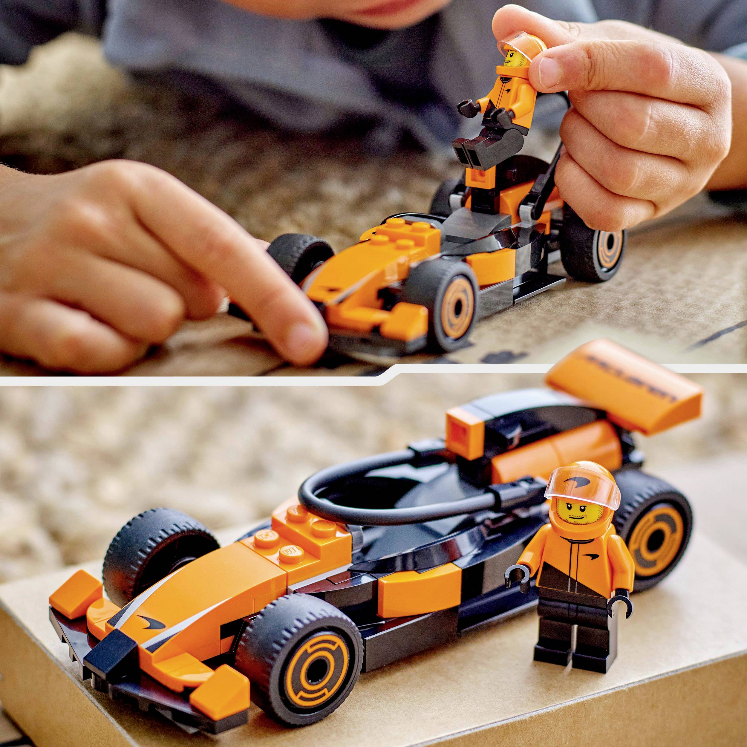 Een kind speelt met een gedetailleerde, oranje-zwarte speelgoedauto en een bijpassende figuur. De auto staat op een kartonnen doos.