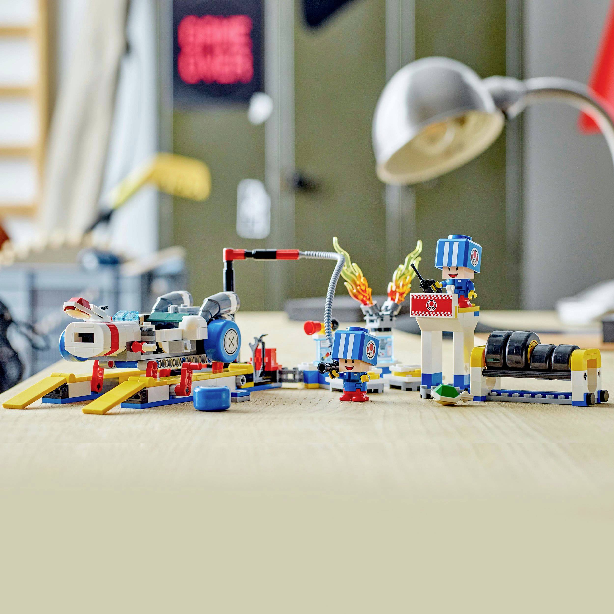 Kleurrijke Lego-robots en -machines op een tafel in een moderne ruimte, verlicht door een bureaulamp.