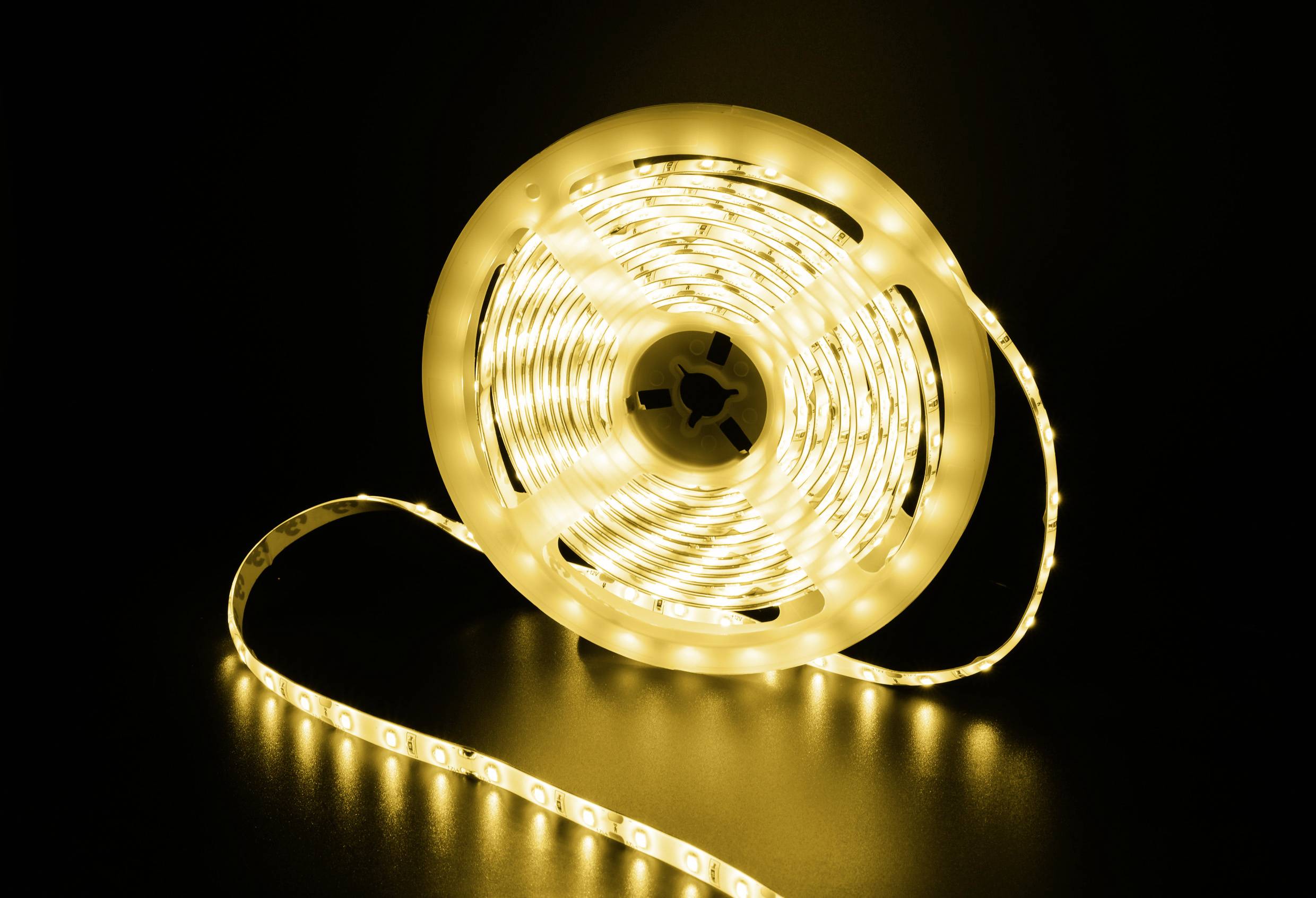 Een opgerolde LED-lichtslinger schijnt warmwit op een donkere achtergrond.