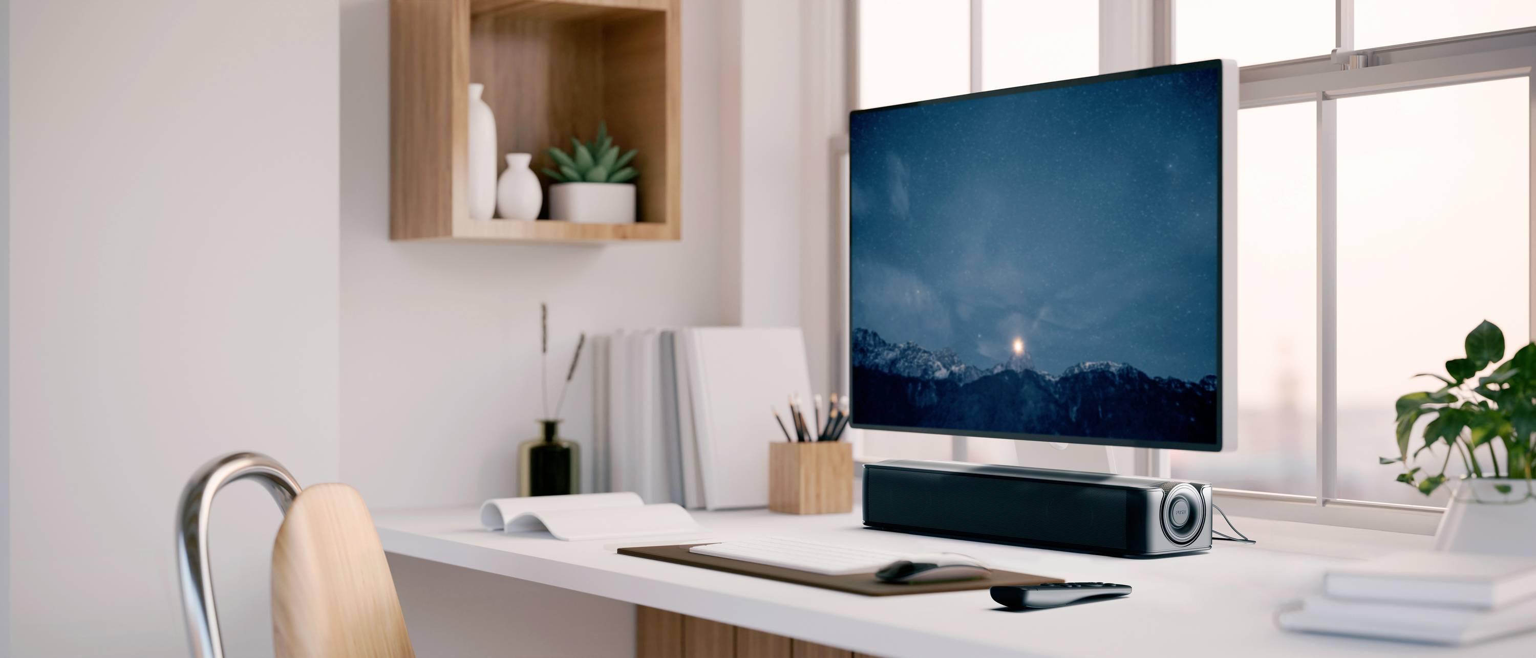 Moderne bureau met computerbeeldscherm, toetsenbord, speakers en planten; rustige, goed verlichte werkomgeving.