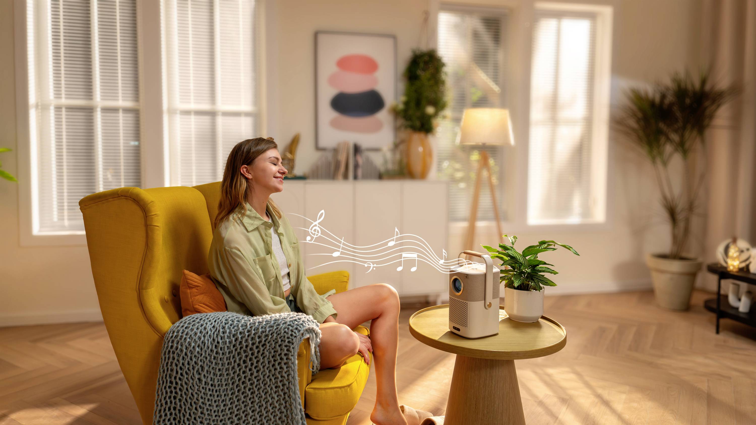 Een vrouw zit glimlachend in een gele fauteuil in een gezellige woonkamer. Een jukebox speelt muzieknoten in de lucht.