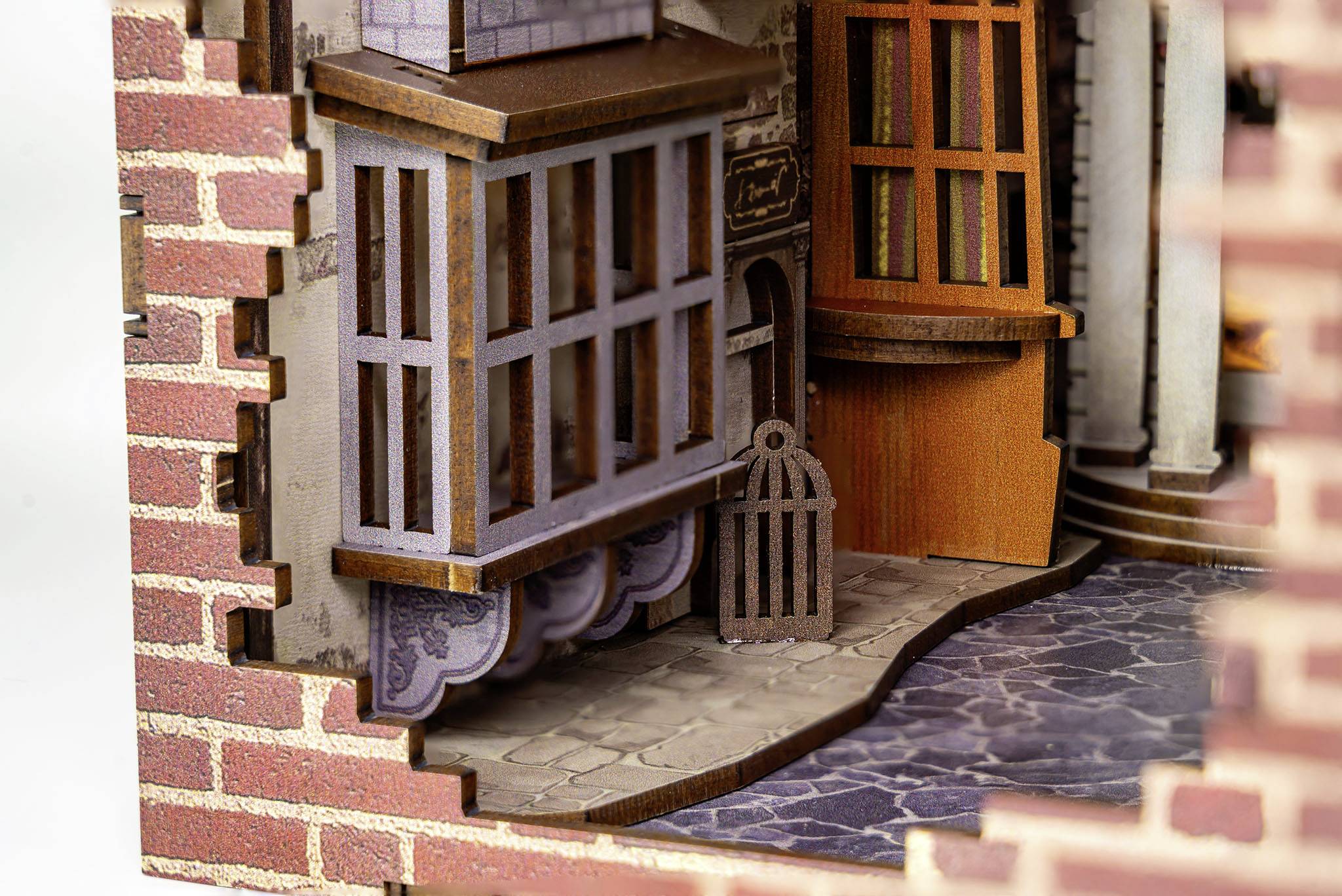 Het beeld toont een gedetailleerd miniatuurmodel van een gebouwhoek met bakstenen muren, ramen en een bestrate stoep.