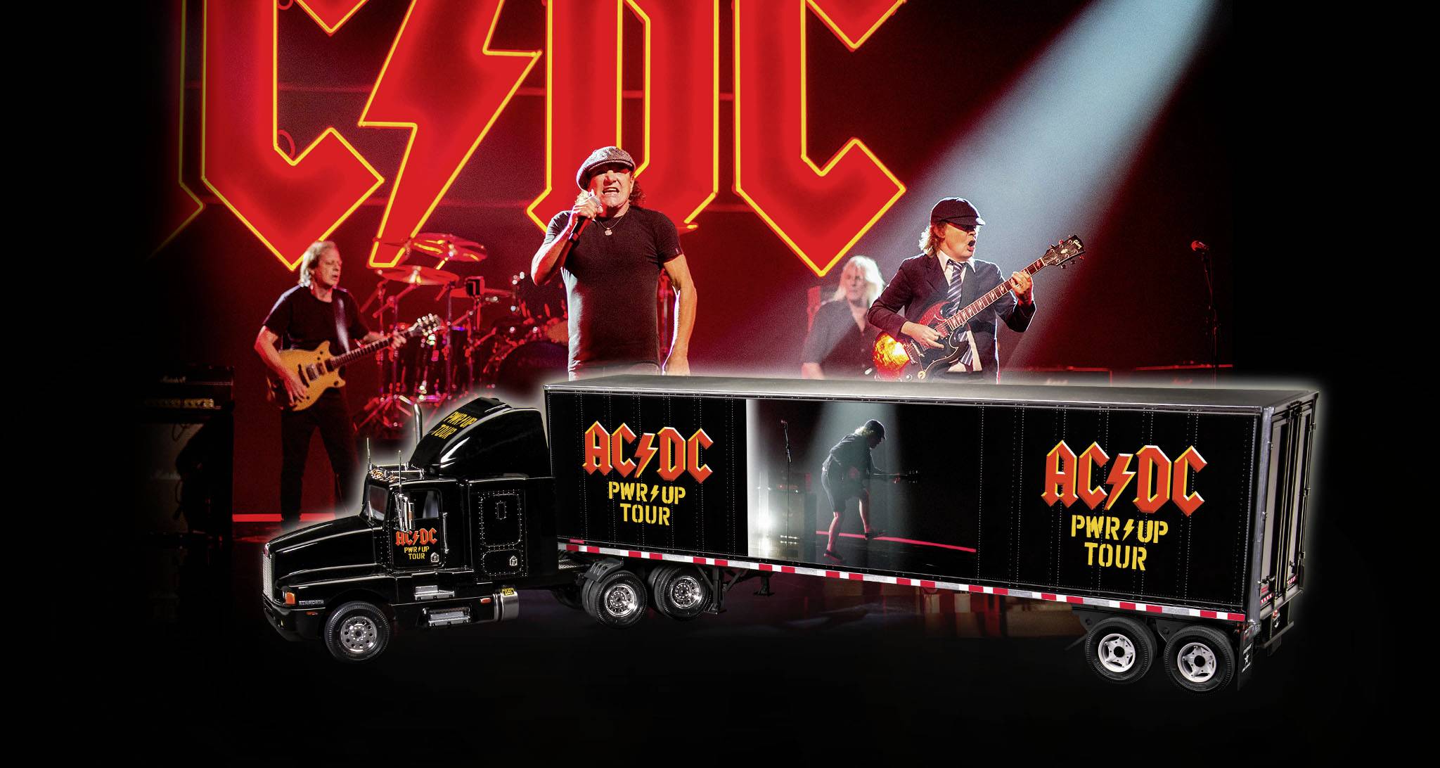Een rockband speelt op het podium. Op de voorgrond staat een verlichte vrachtwagen met het bandlogo en de tekst 'PWR/UP Tour'.