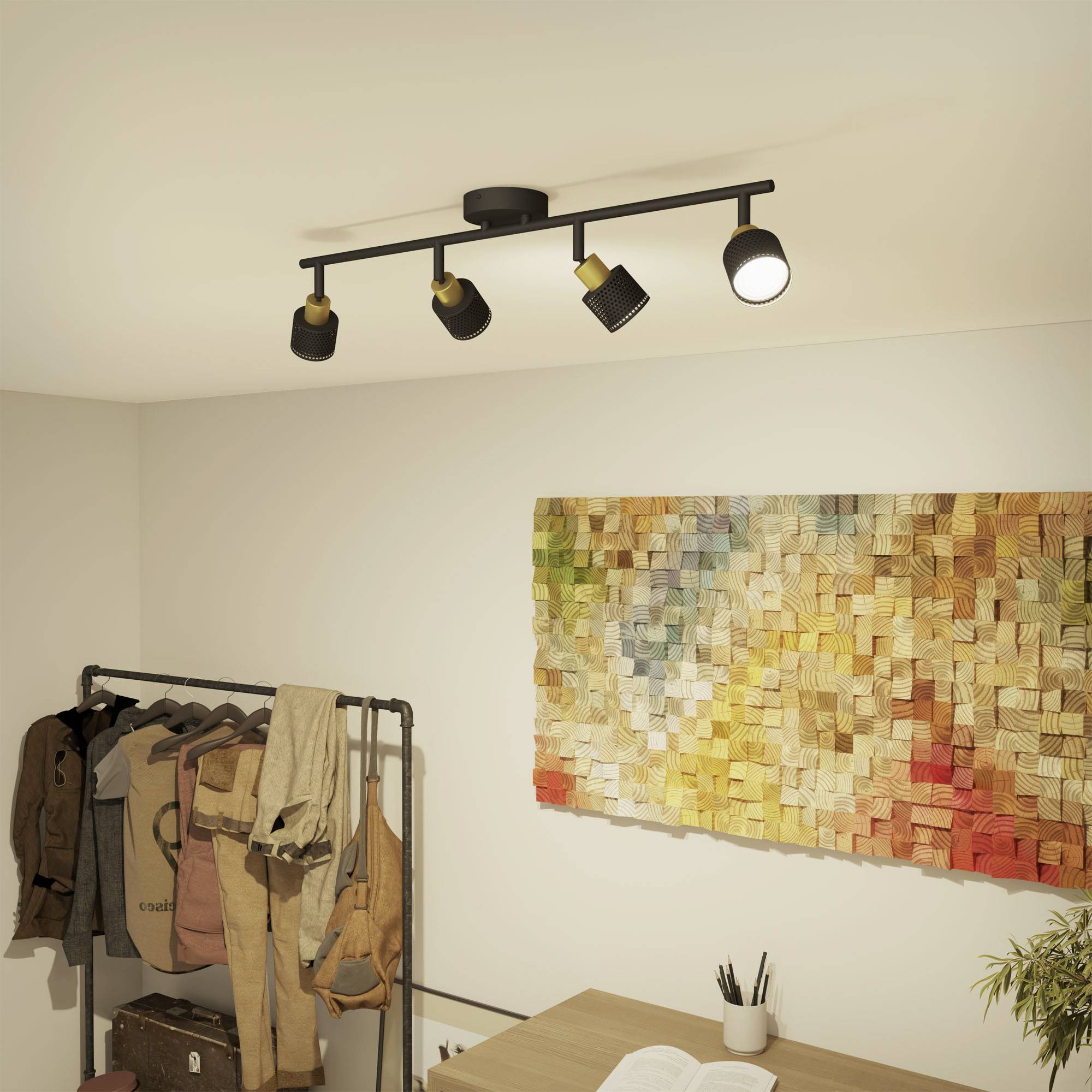 Een ruimte met lichte muren, een kleurrijk mozaïekkunstwerk aan de muur, een kledingrek met kleding en een tafel met pennen.