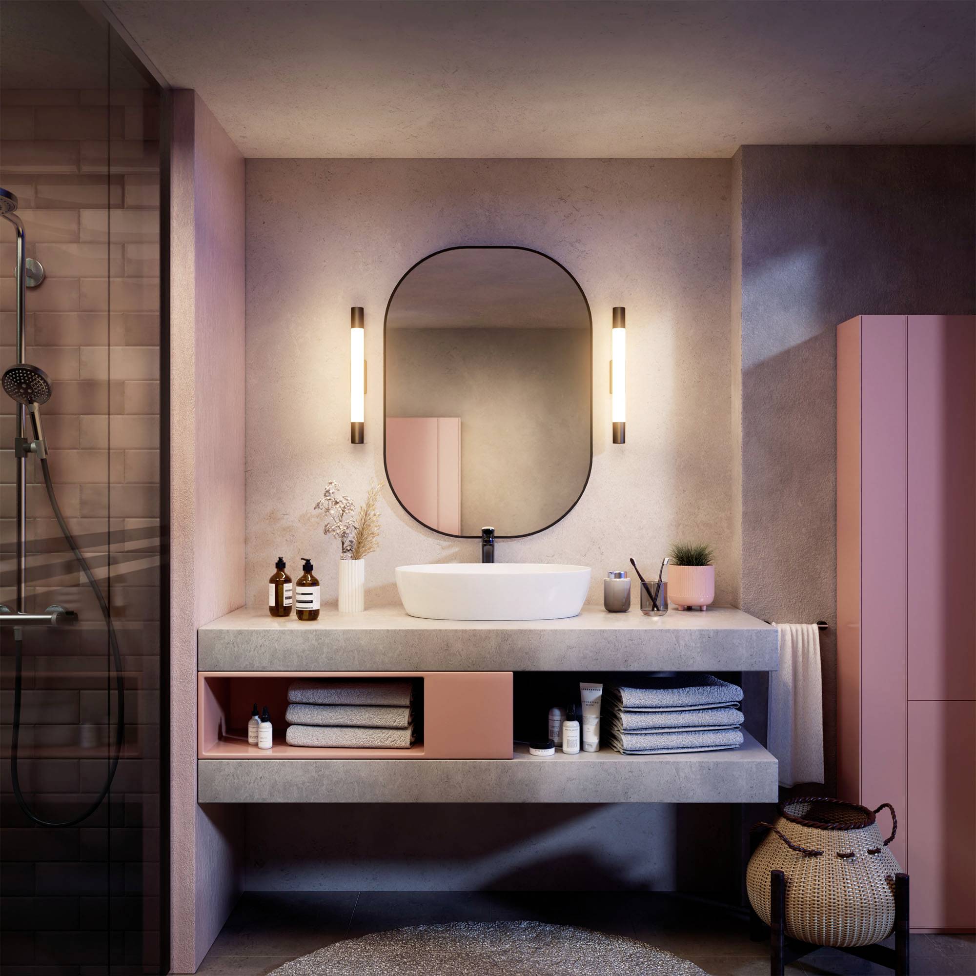 Modern badkamer met roze accenten, een ovale spiegel boven een wastafel, verlicht door wandlampen, en een douche links.