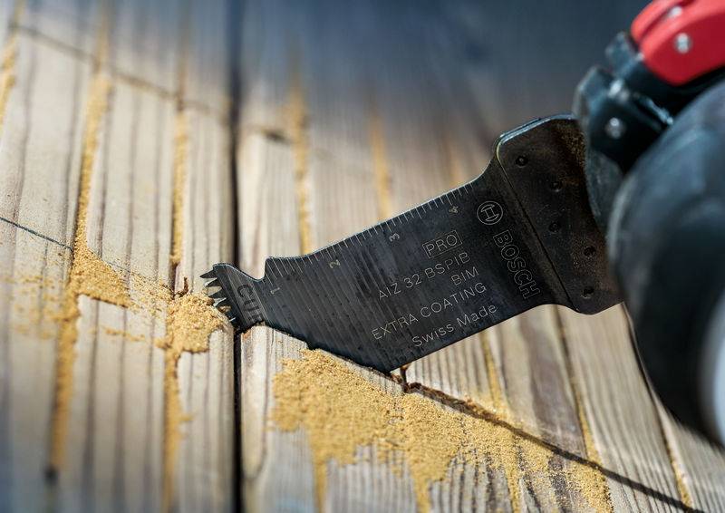 Een oscillerend gereedschap snijdt hout, terwijl zaagsel op het oppervlak valt.