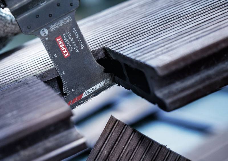 Close-up van een zaagblad dat houten planken doorsnijdt. Het zaagblad is gemarkeerd met 'EXPERT' en behoort tot een Bosch-gereedschap.