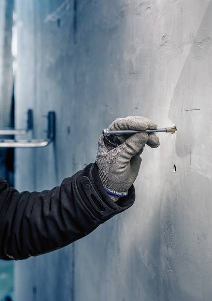 'Hand in handschoen houdt pen vast en tekent op lichte muur.'