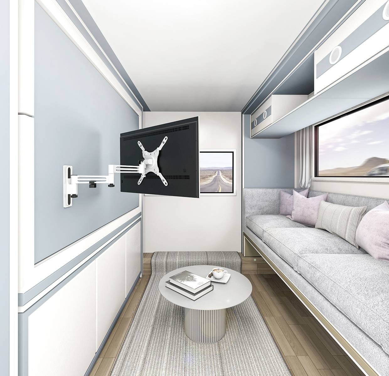 Een moderne, kleine woonruimte met een grijze bank, een ronde salontafel en een aan de muur gemonteerde televisie. Raam met uitzicht op de woestijn.