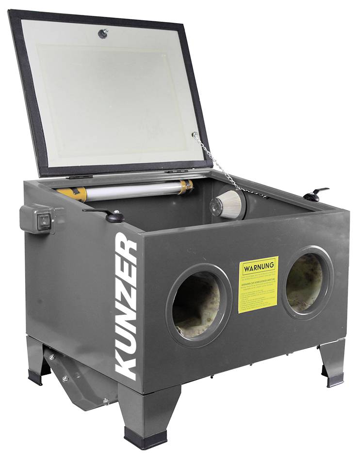 'Zandstraalmachine met twee handschoenopeningen en glazen afdekking bovenaan. Merk Kunzer. Geel waarschuwingsbord aan de voorzijde.'