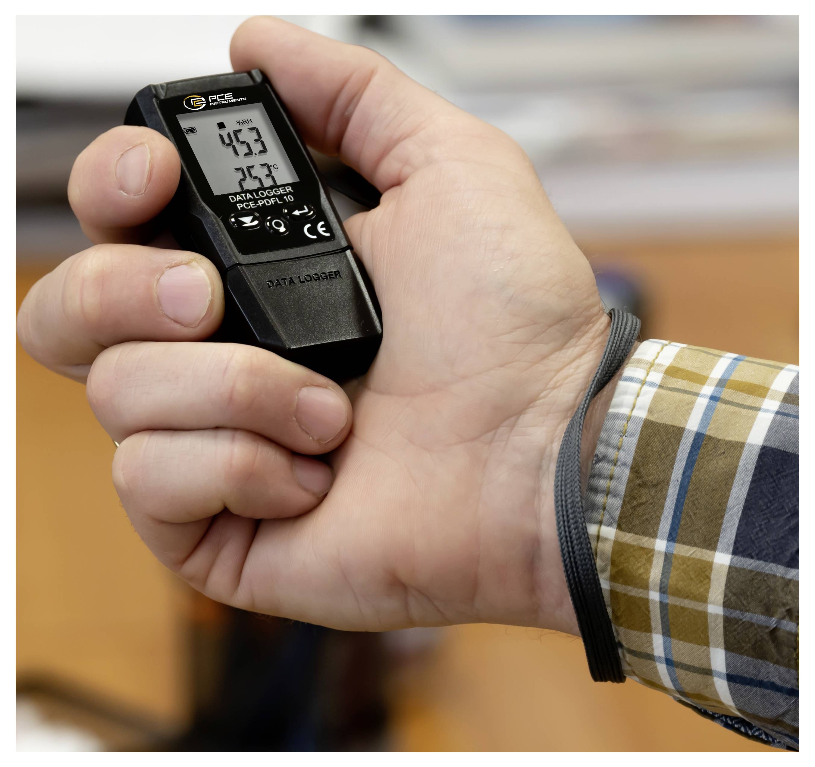 Hand die een kleine digitale datalogger vasthoudt met een scherm dat metingen toont '4.53' en '23.7', waarschijnlijk temperatuur- en vochtigheidsuitzettingen.