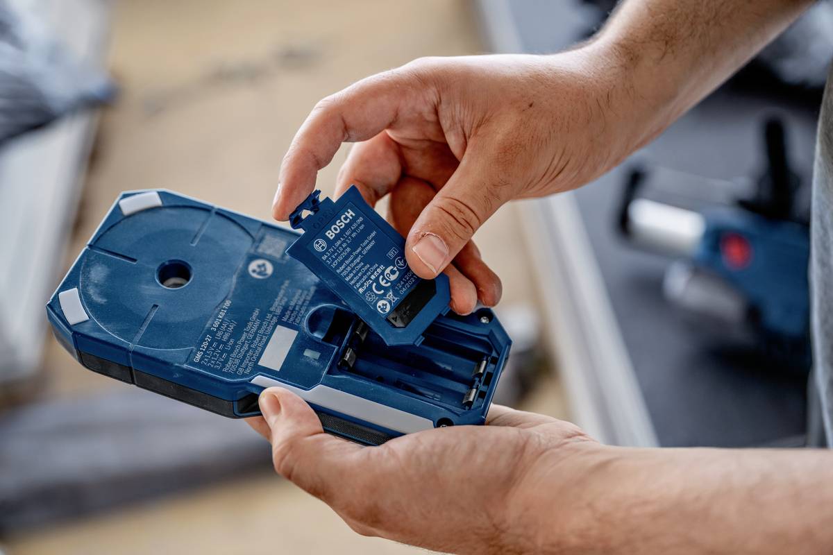 Een persoon plaatst een Bosch-accu in een elektronisch apparaat. Het apparaat en de accu zijn blauw.