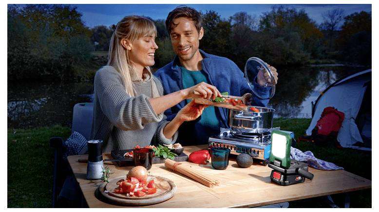 Stel dat buiten de camping plaats kookt, voedsel in een pot op een draagbaar fornuis naast een verlichte lantaarn en campinguitrusting plaatst.