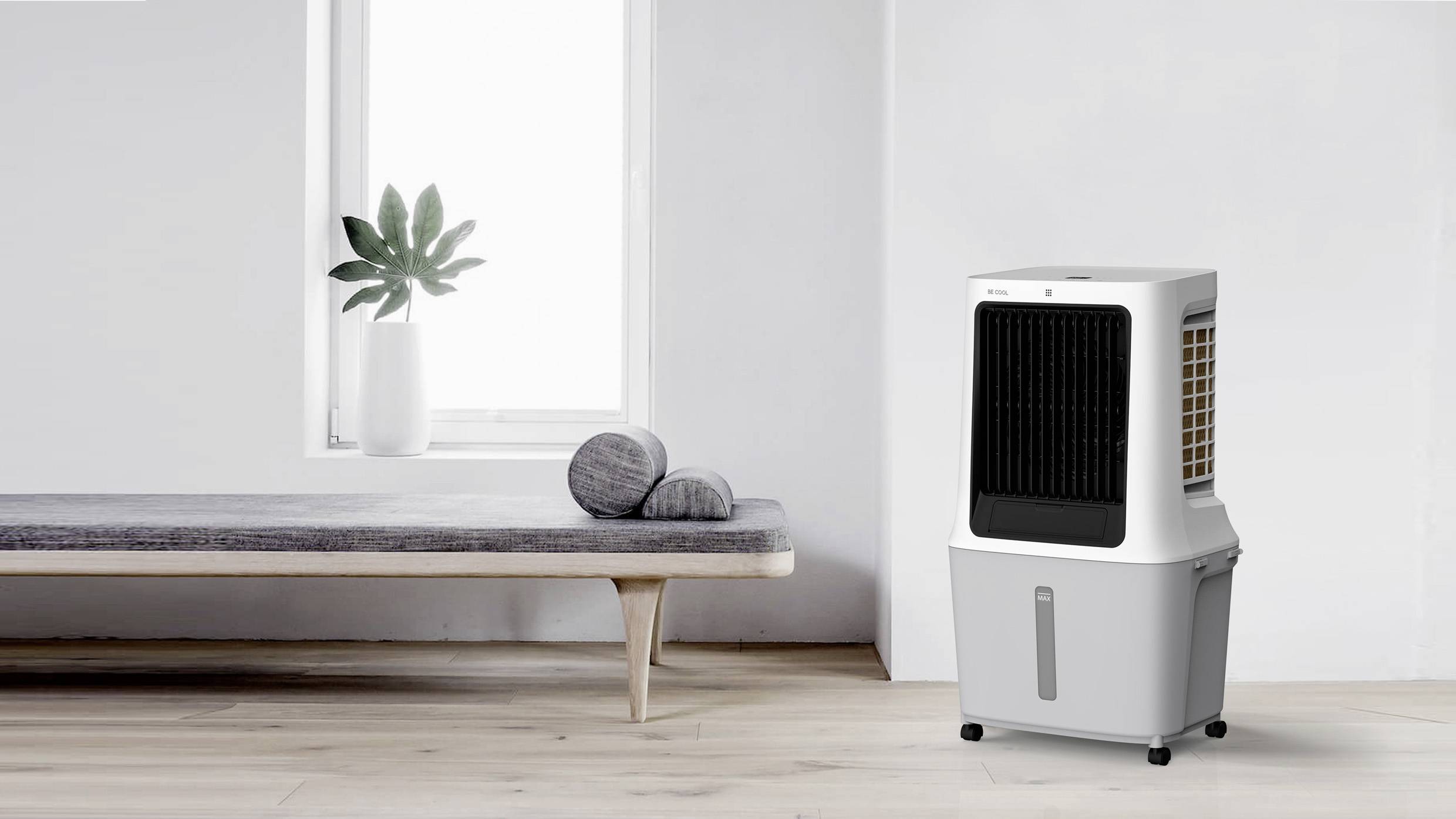 Een luchtverdeler staat in een moderne, minimalistisch ingerichte ruimte met een houten vloer. Naast de verdeler liggen grijze kussens op een bank.