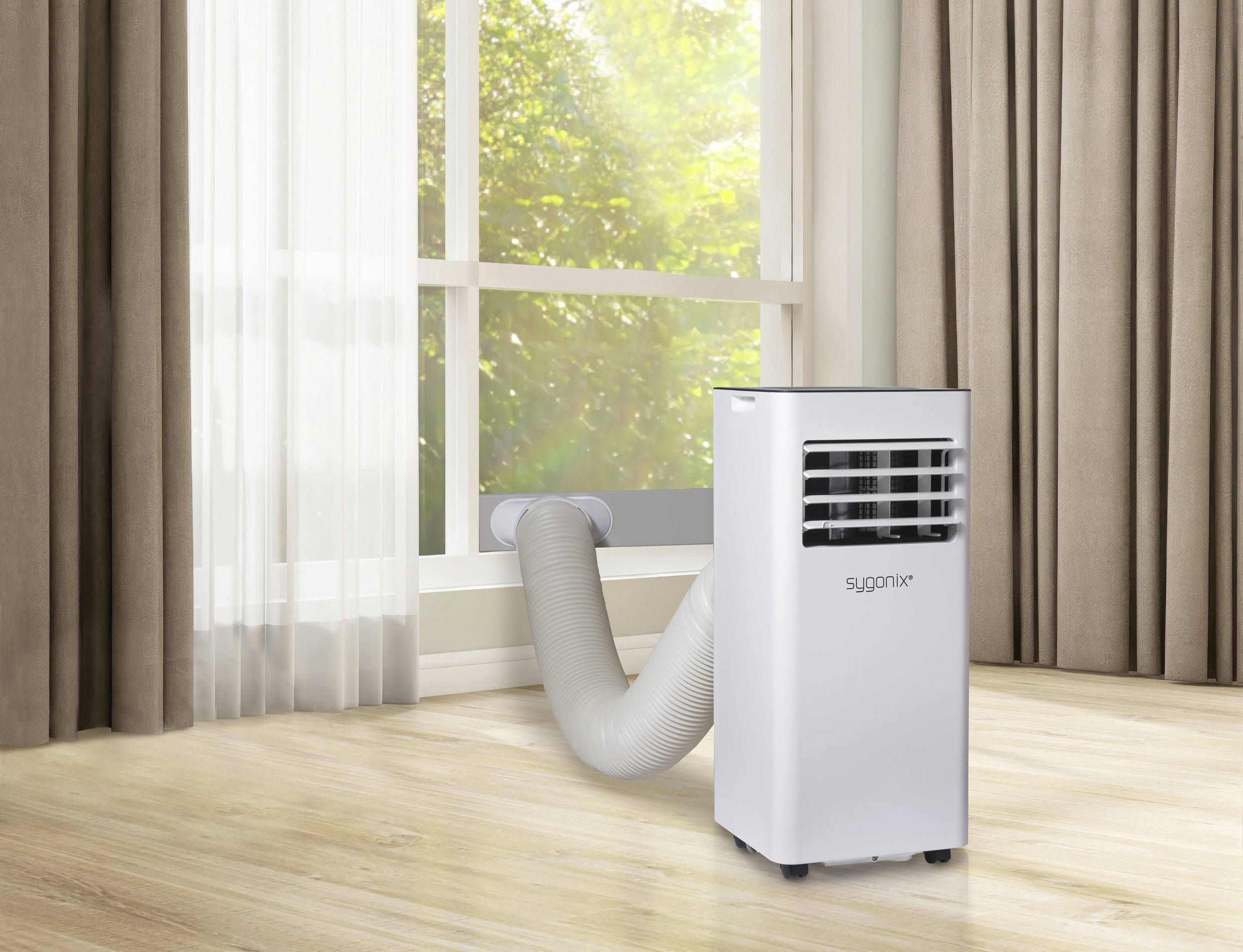 Mobiele airconditioning in een ruimte, met een afvoerslang die door een raam loopt. Zonlicht schijnt door het raam.