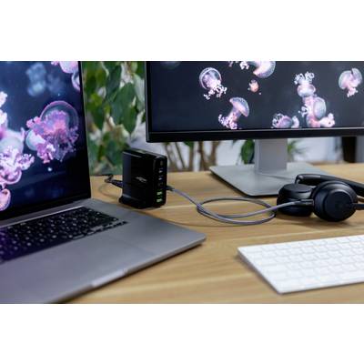 Werkplek met laptop, twee monitors, koptelefoon en een USB-hub op een bureau. Monitors tonen kwallenfoto's.