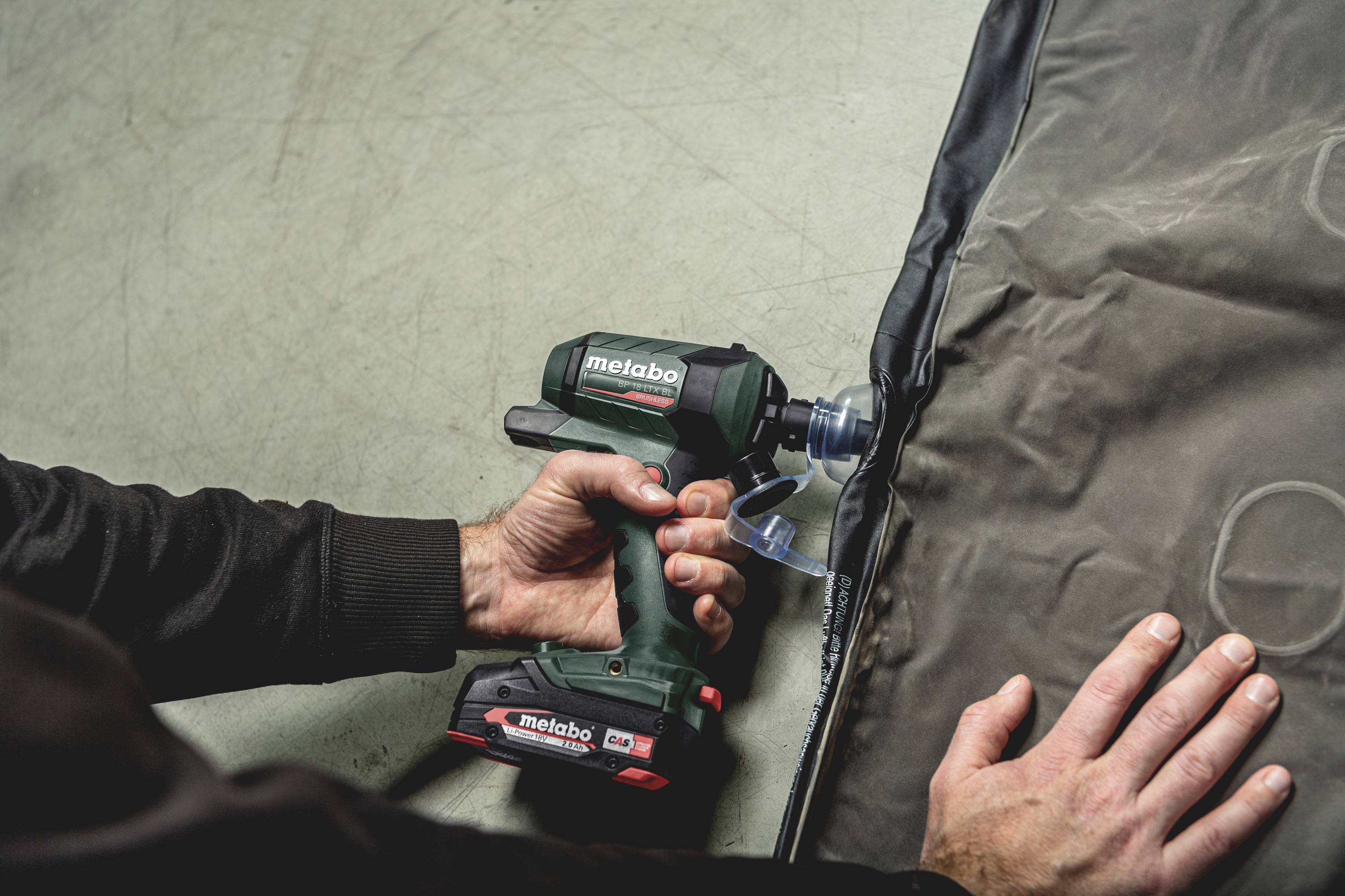 Een persoon gebruikt een accuboormachine op een oppervlak. Metabo-logo op het apparaat. De boormachine lijkt een taak uit te voeren aan een rand.