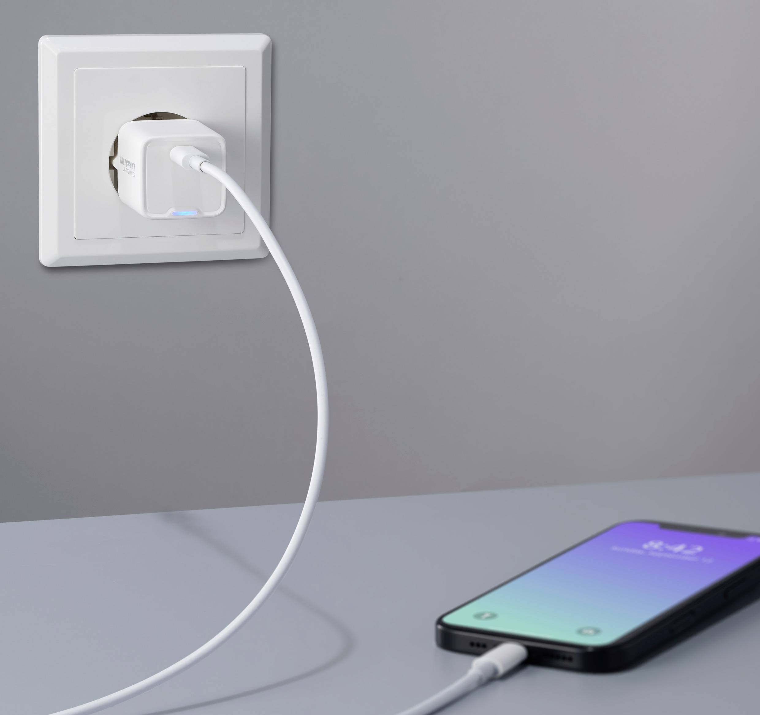 Een smartphone wordt aangesloten op een stopcontact met een oplaadkabel.