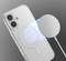 Smartphone met transparante behuizing wordt draadloos opgeladen op een rond oplaadstation tegen een grijze achtergrond.