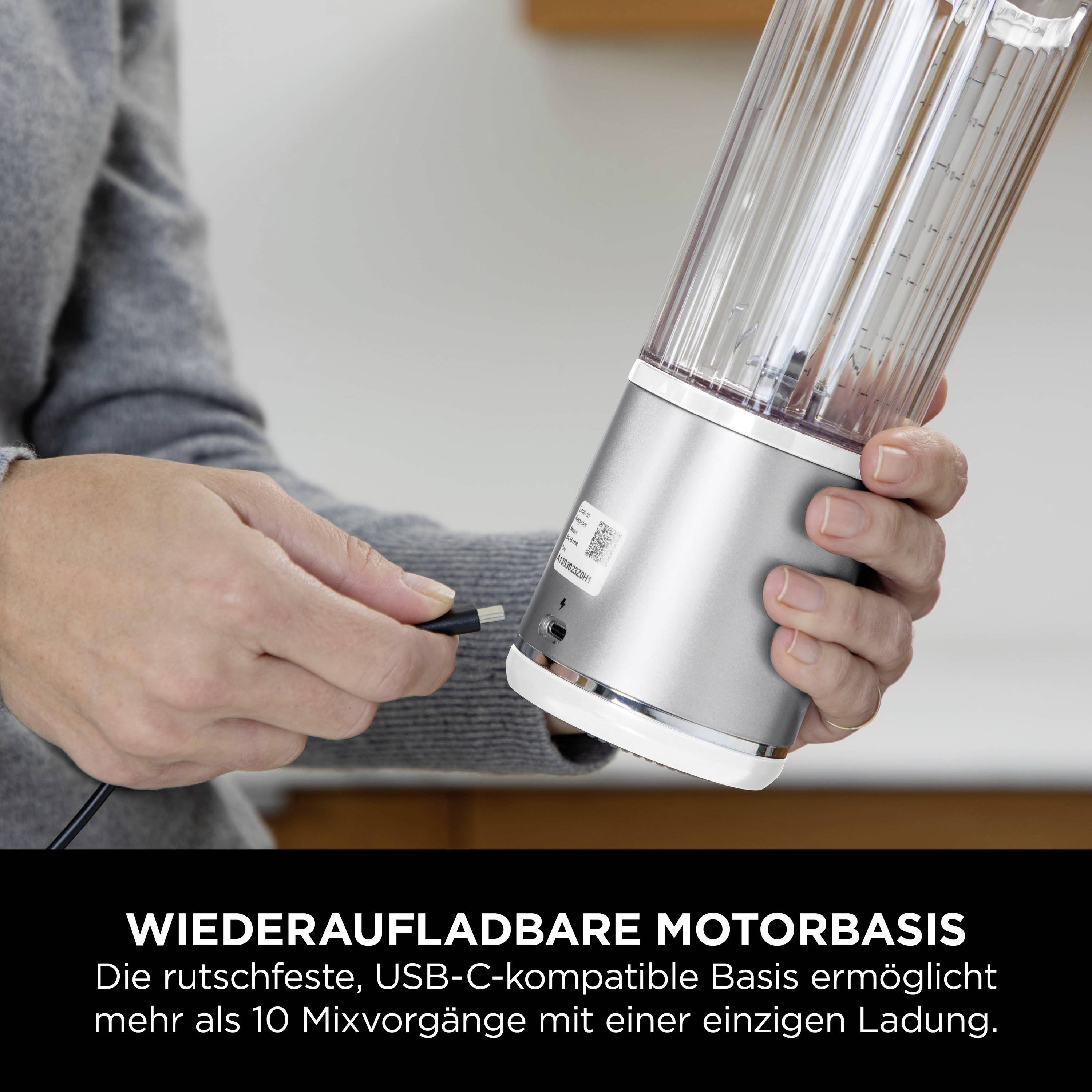 Een persoon houdt het verwijderbare deel van een oplaadbare mixer vast terwijl hij een USB-C-kabel aansluit voor het opladen. Tekst: 'Oplaadbare motorbasis'.