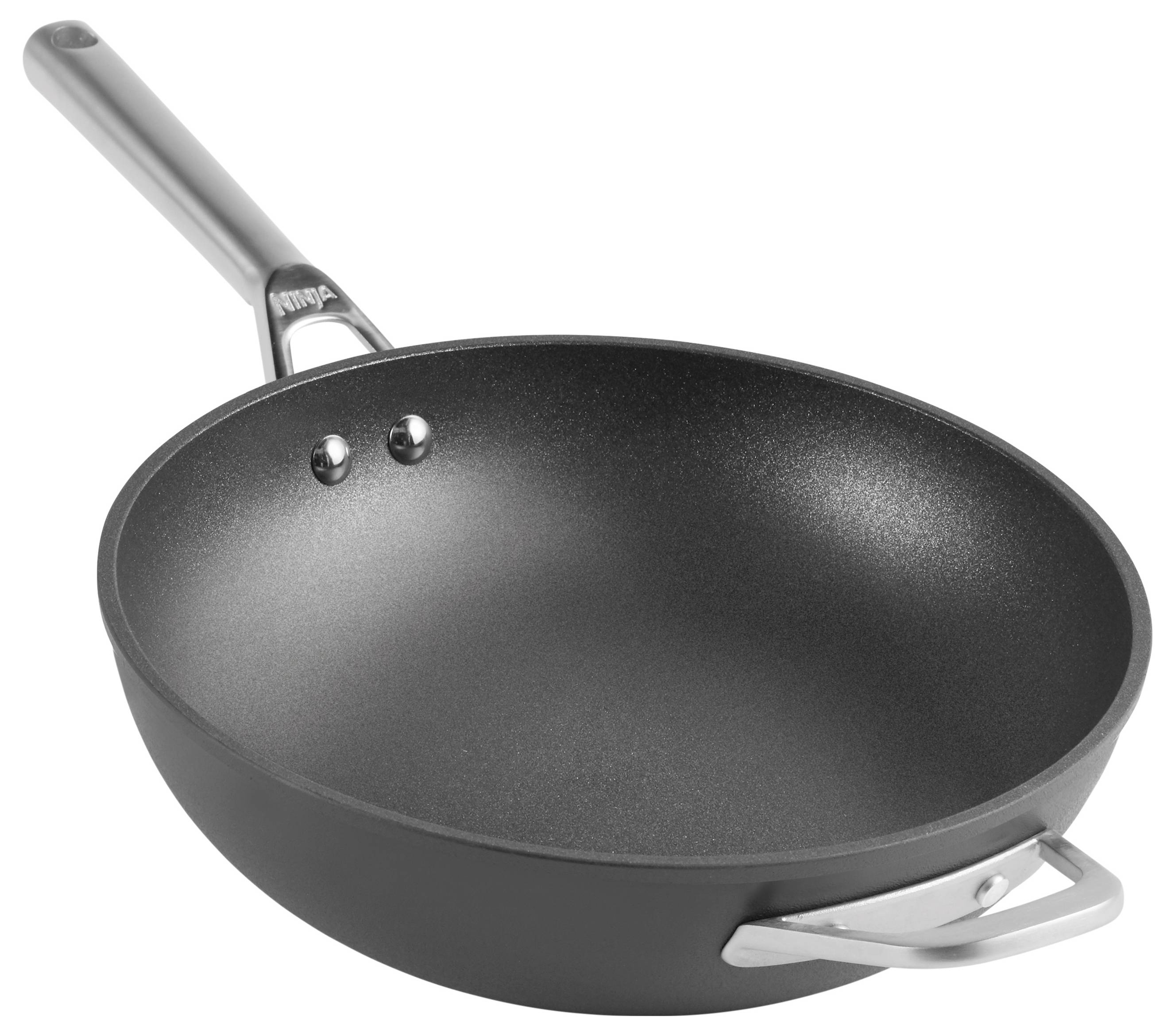 Een lege, zwarte koekenpan met een lange, zilveren steel, liggend op een lichte ondergrond.