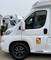 Een wit camper met een sticker waarop 'Attention - Angles Morts' staat, staat geparkeerd op een camper-tentoonstelling.
