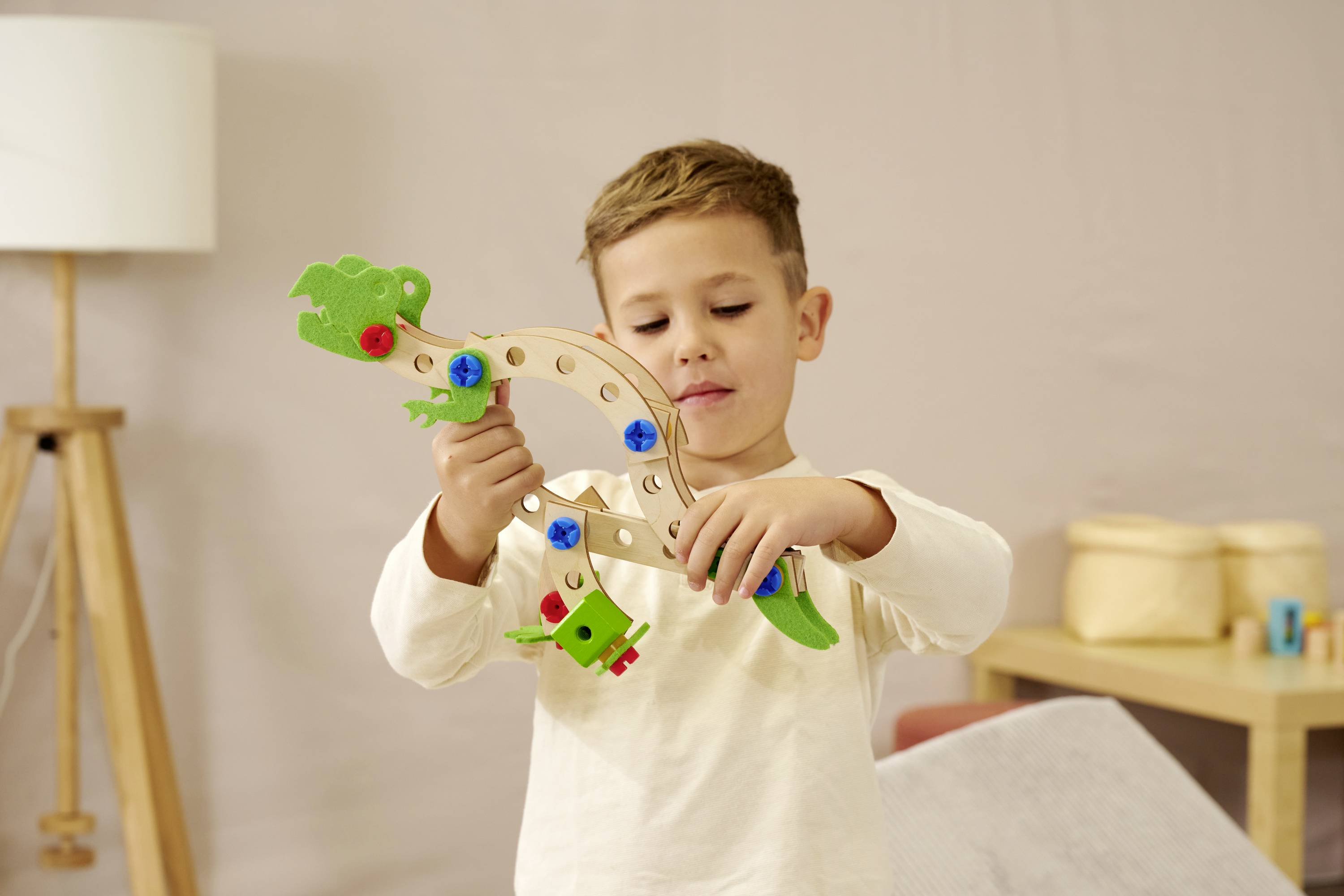 Een kind speelt met een houten bouwset in de vorm van een draak in een gezellige ruimte.