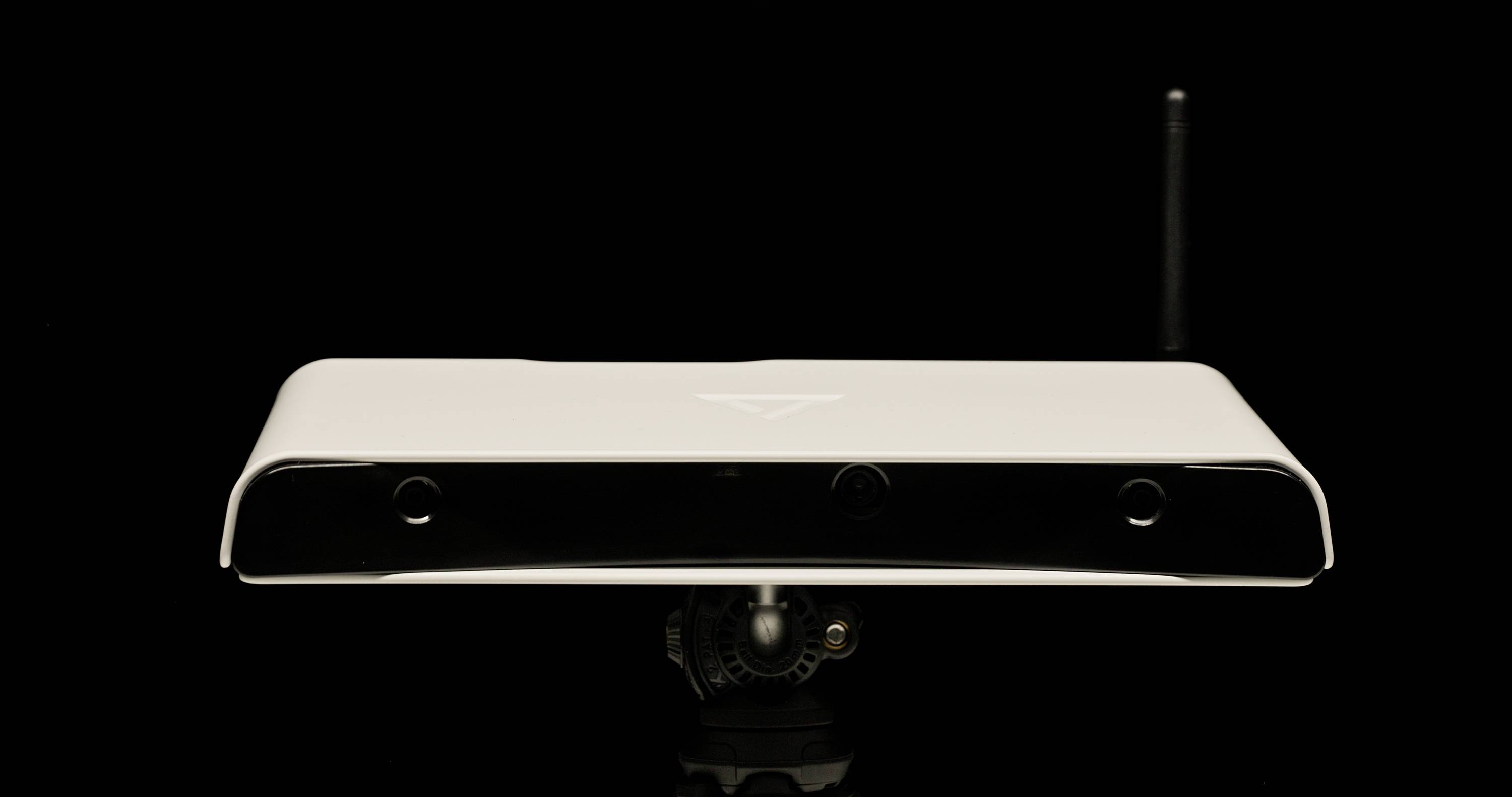 Een rechthoekig, wit technisch apparaat met een zwarte voorste camera, voorzien van een klein logo. Bedoeld voor digitale herkenning.