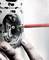 Een hand installeert een stopcontact in een metalen frame, waarbij een schroevendraaier met een rode handgreep wordt gebruikt.