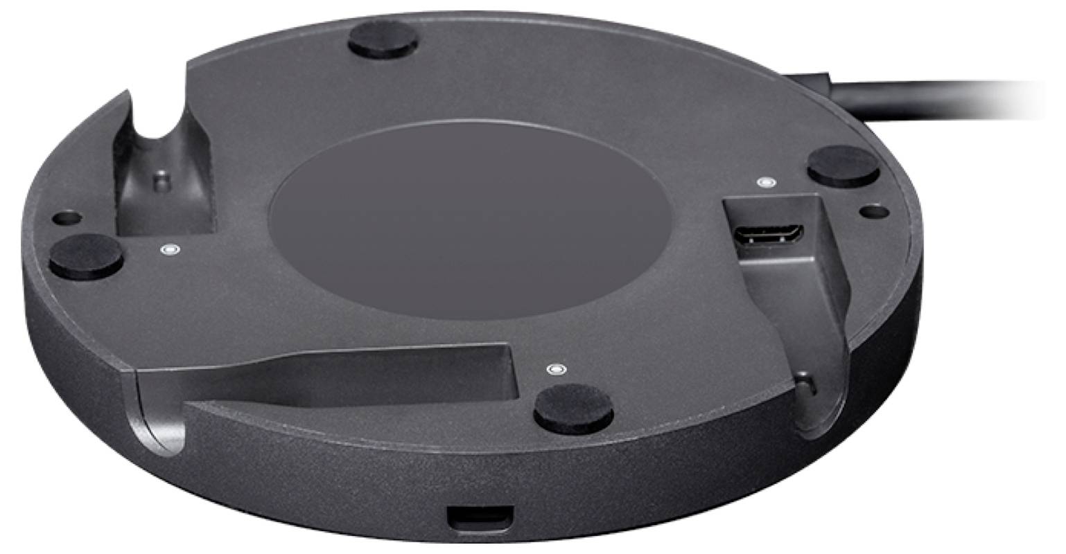 Rond, zwart-grijs apparaat met meerdere aansluitingen, waaronder USB en HDMI, geplaatst op een glad oppervlak.