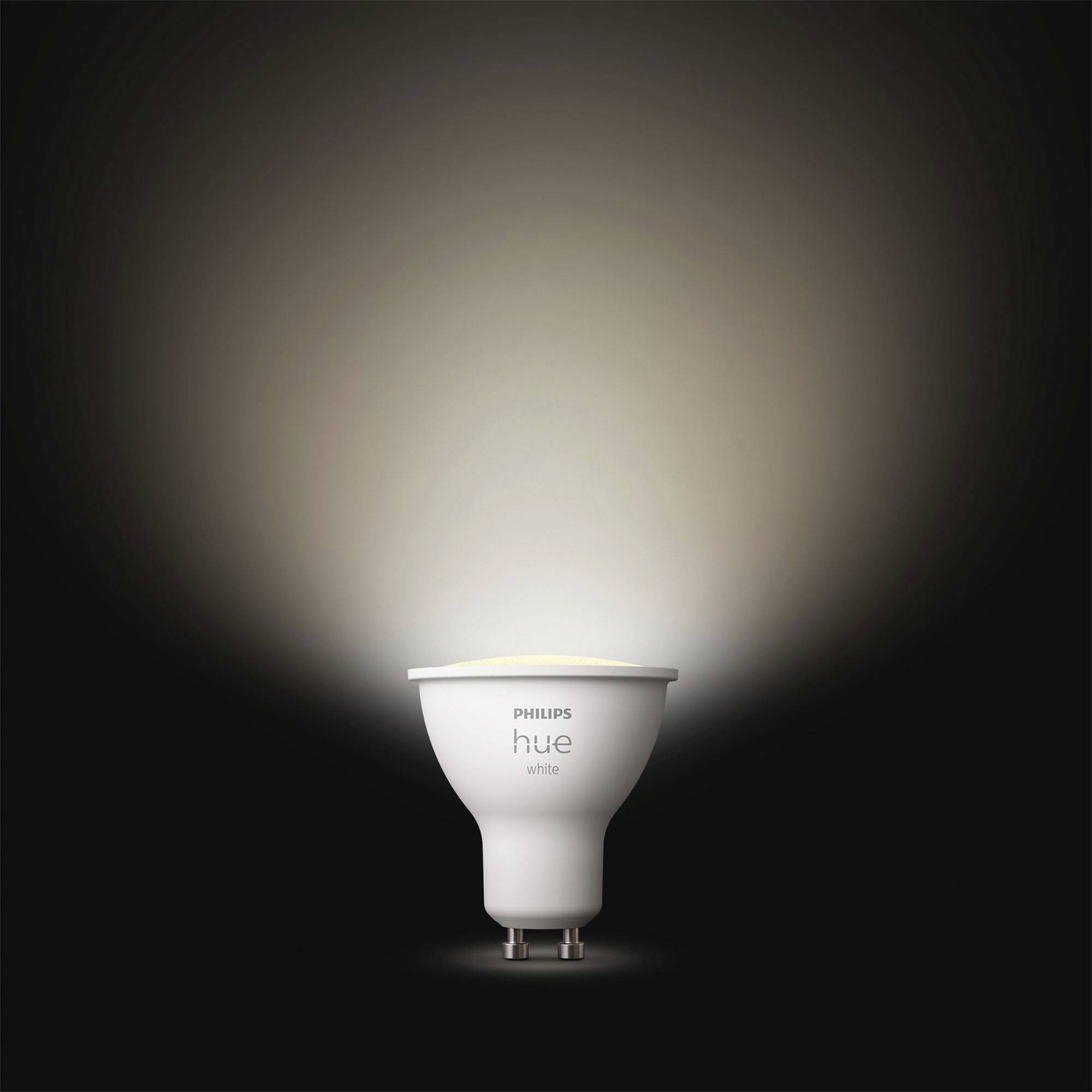 Een Philips Hue-lamp straalt warm wit licht op een donkere achtergrond.