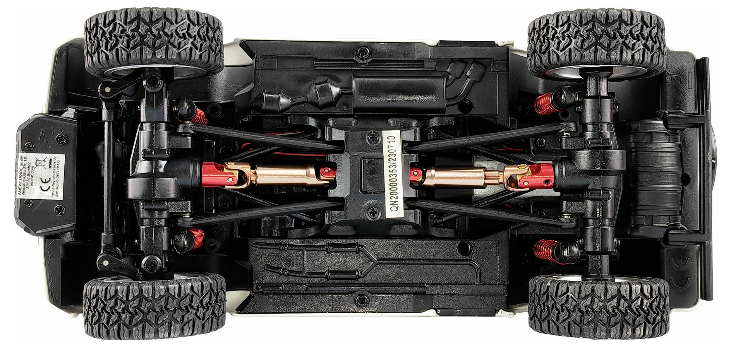 Speelgoedauto van onderen, toont vering en assen. Vier grote wielen en gedetailleerde mechaniek zichtbaar.