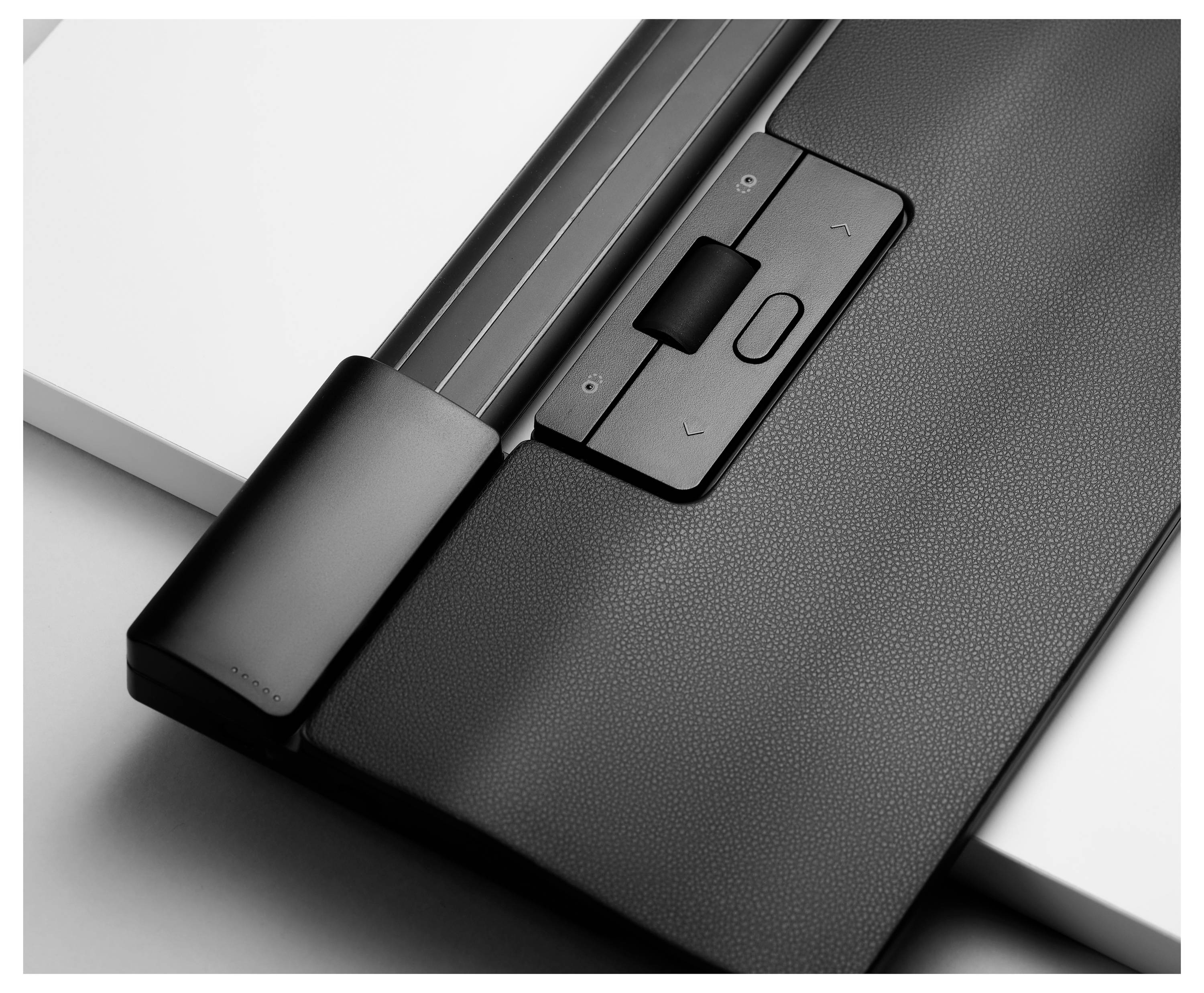 Zwart-wit beeld van een modern toetsenbordonderdeel met trackpad en twee knoppen. Een slanke, minimalistische vormgeving wordt getoond.