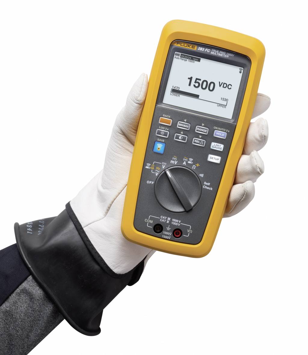 Een gehandschoende hand houdt een multimeter met een digitaal display vast. Het display toont '1500 VDC'.