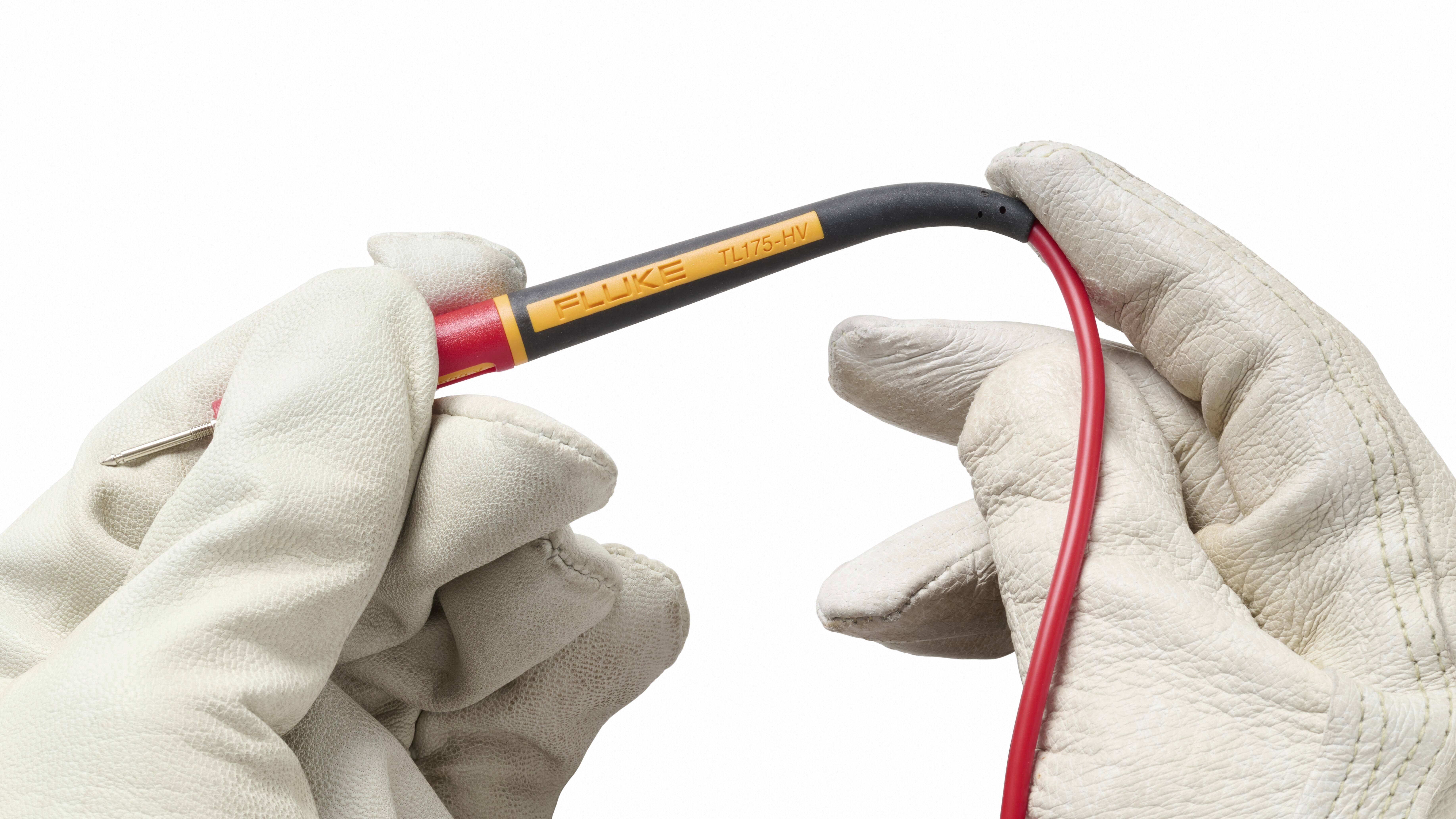 Twee handen in witte handschoenen houden een meetapparaat met een rood snoer. Het apparaat wordt gebruikt voor elektrische metingen.