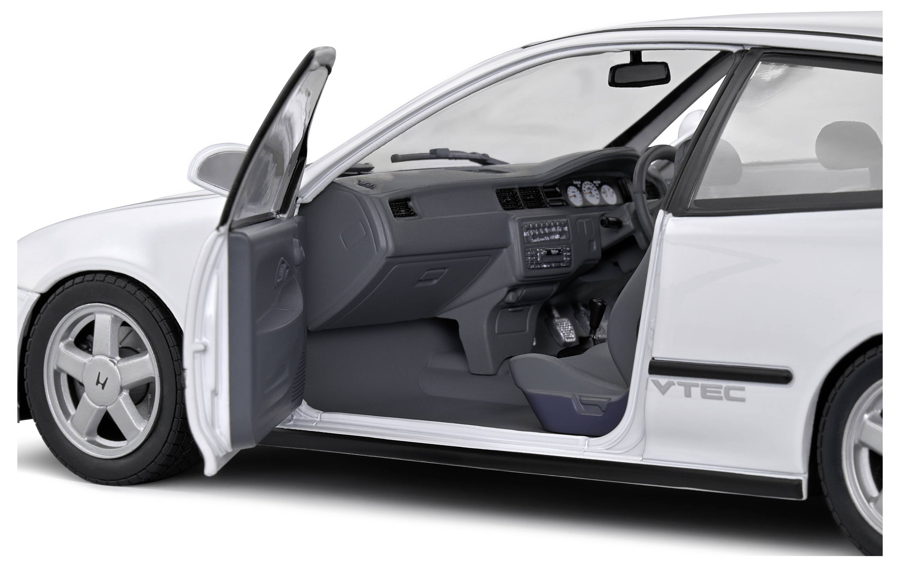 Witte auto met geopende bestuurdersportier, waarbij het stuurwiel, dashboard en VTEC-opschrift aan de zijkant zichtbaar zijn. Interieur duidelijk te zien.