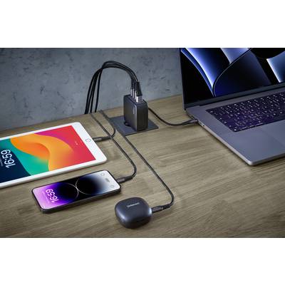 Een tablet, twee smartphones en een laptop zijn aangesloten op een USB-laadadapter die op een houten tafel staat.