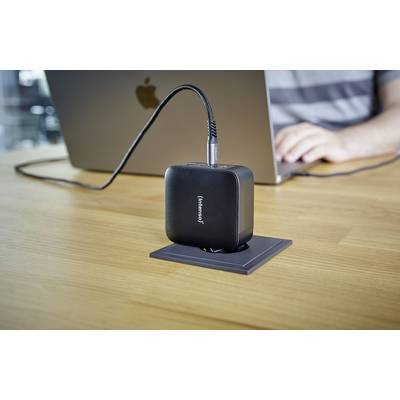 Een persoon werkt op een laptop terwijl een zwarte oplader is aangesloten op een stopcontact in de tafel.