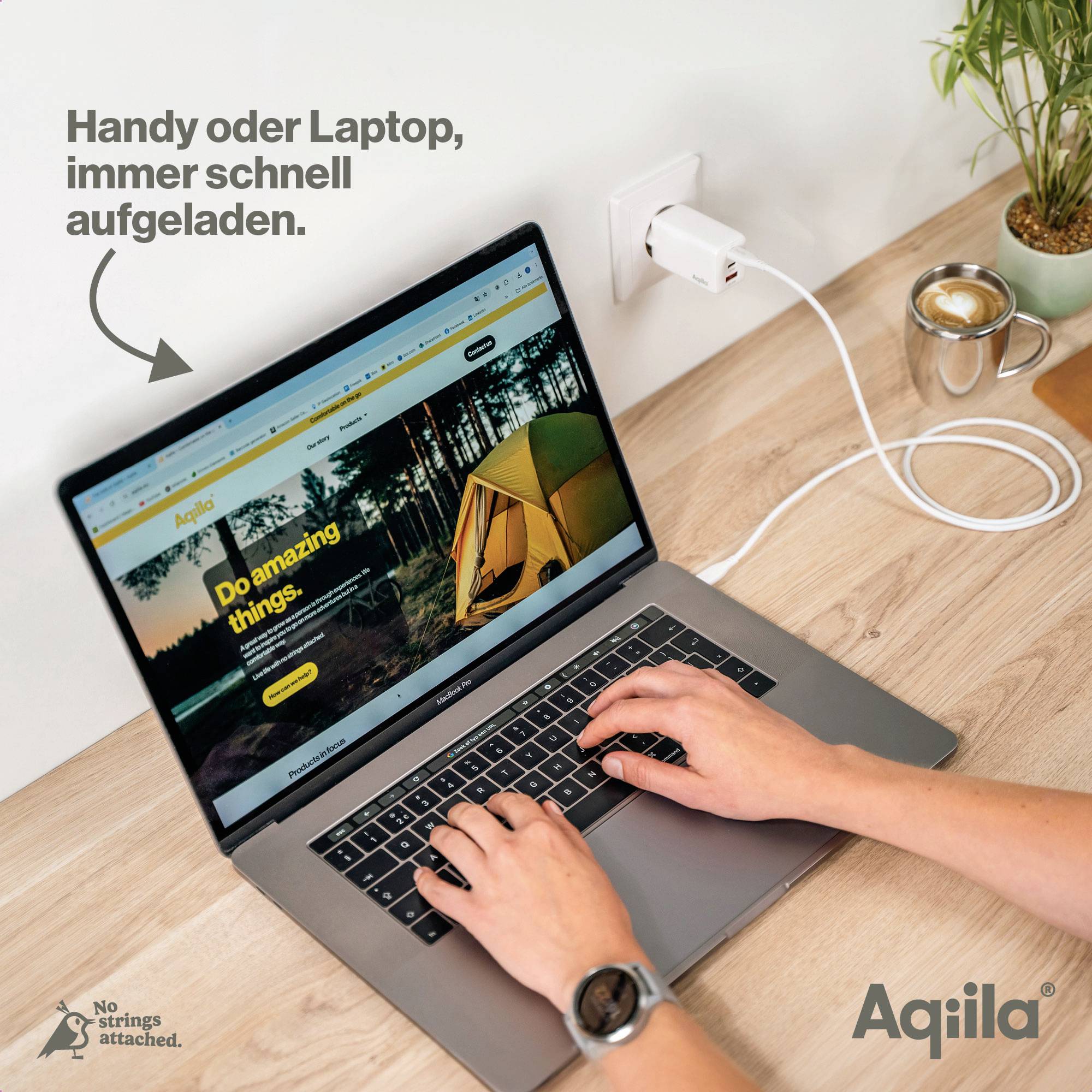 Een persoon laadt een laptop op aan een stopcontact in de muur. Op het scherm staat 'Doe geweldige dingen'. Naast de laptop ligt een mobiele telefoon.