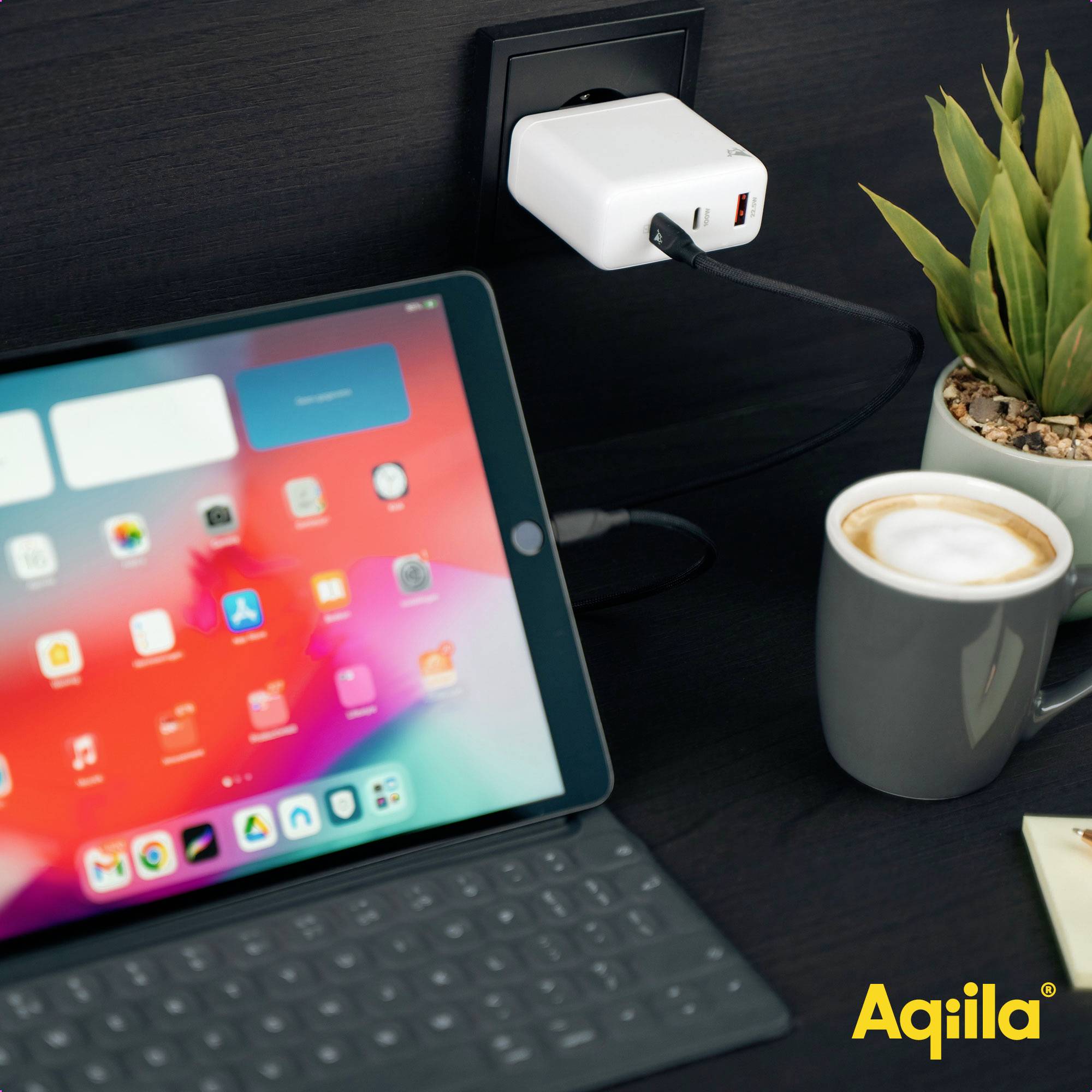 Tablet op een bureau met een afneembaar toetsenbord, een oplader is aangesloten op het stopcontact. Naast het tablet staat een kopje koffie.