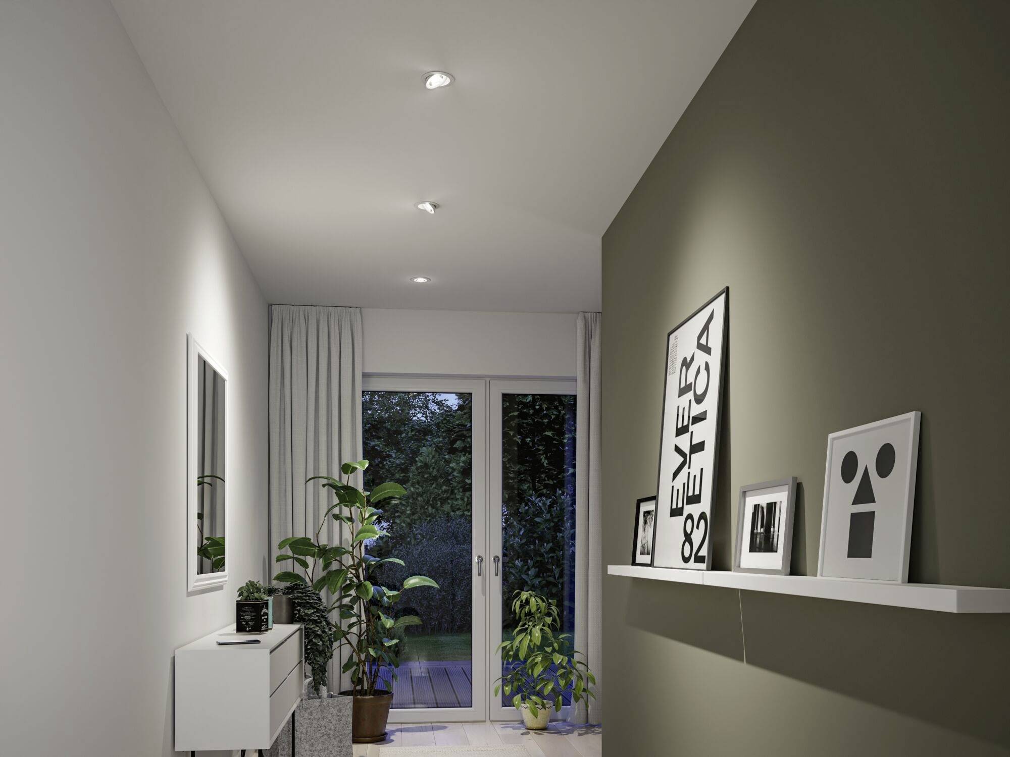 Een modern ingerichte hal met witte muren, planten en kunstwerken. Op de achtergrond zijn glazen deuren die uitkomen op een tuin.